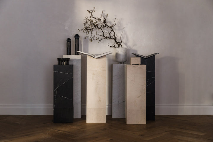Stone pedestals with ribbing on the bottom. Made from marble and limestone holding books and decor.
