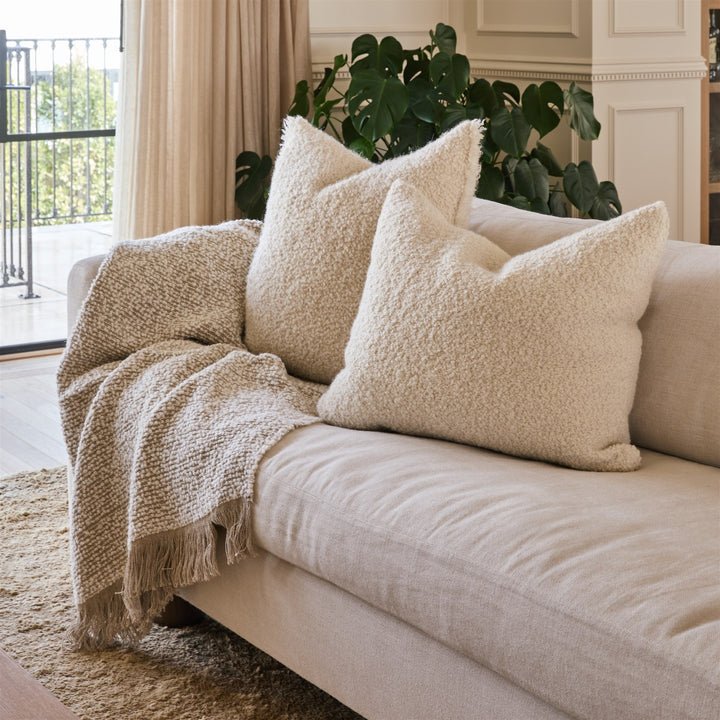 Cream belgian linen pillows with boucle. Cream sofa in a neutral living room.