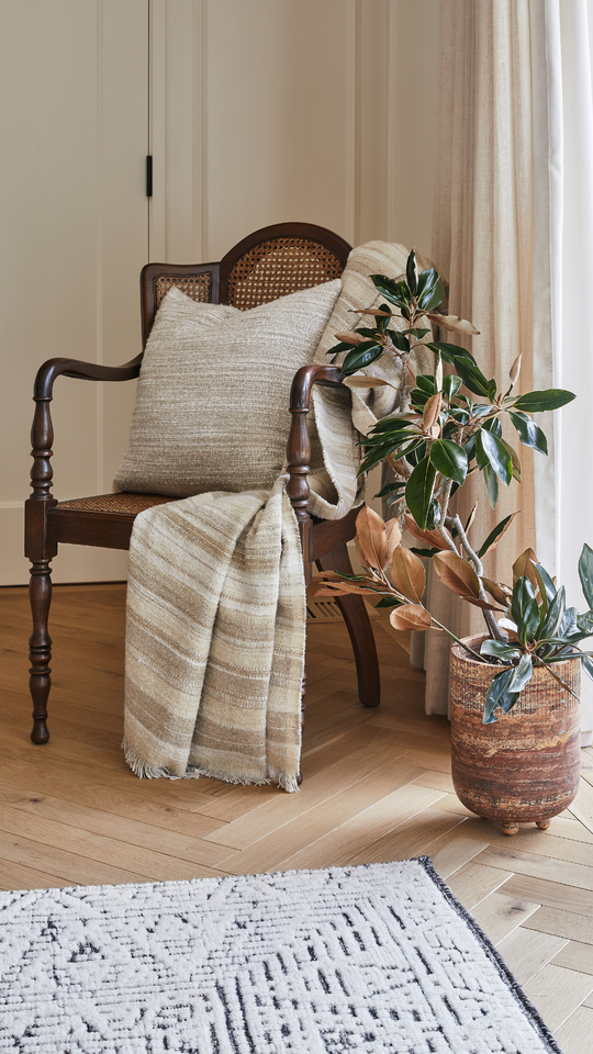 belgian linen pillows and throws next to a vase made of travertine.