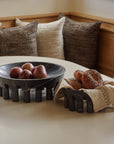Two bowls made from black marble in a breakfast nook holding fresh bagels and apples.